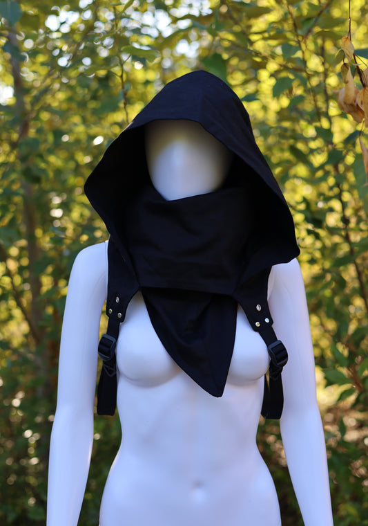 Black hooded garment on a mannequin against a natural background