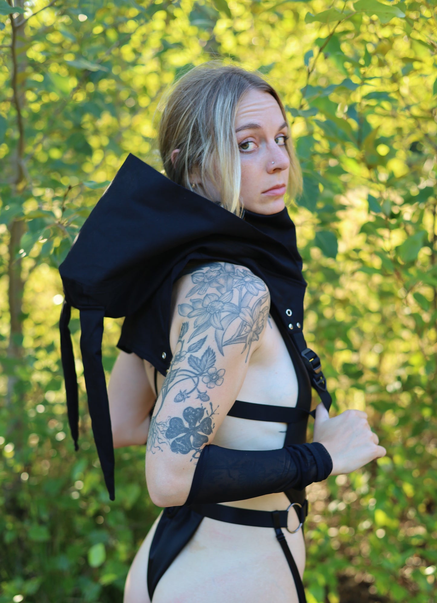 Woman wearing a black outfit with floral tattoos outdoors