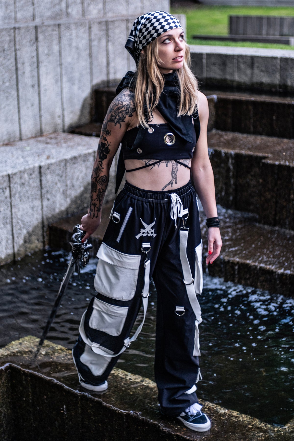 Model wearing black fantasy techwear pants with white utility pockets and detachable straps