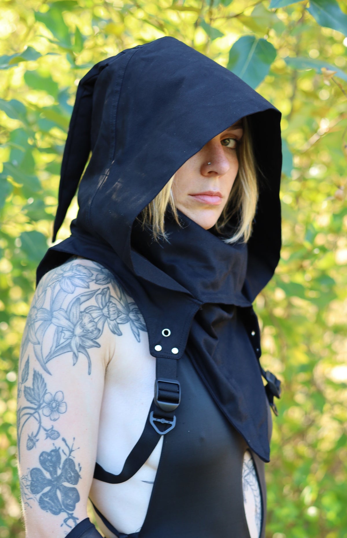 Model wearing the Black Assassin Hood with the hood raised and arm straps secured